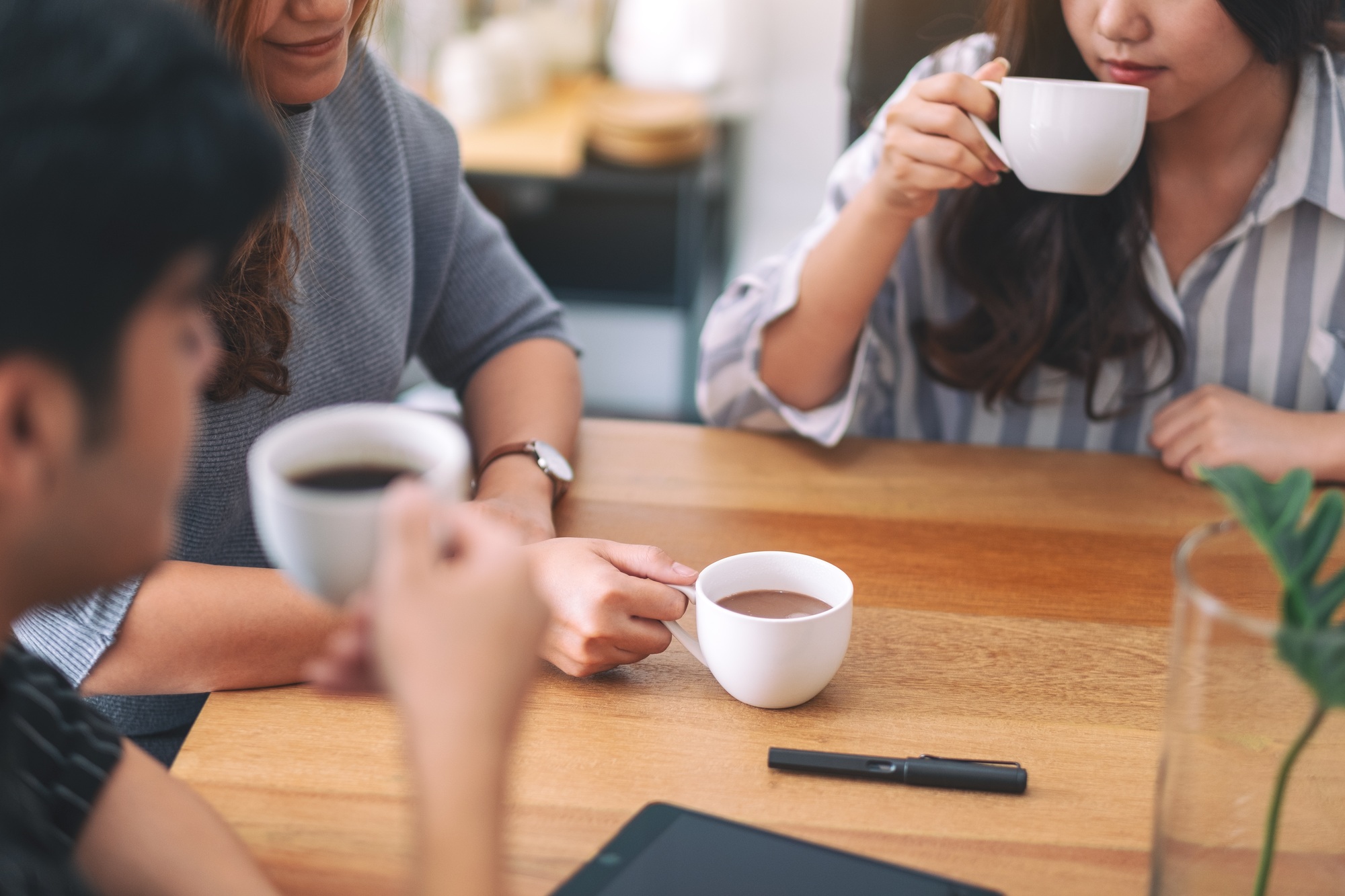 Close up image of three people enjoyed drinking coffee while meeting in office